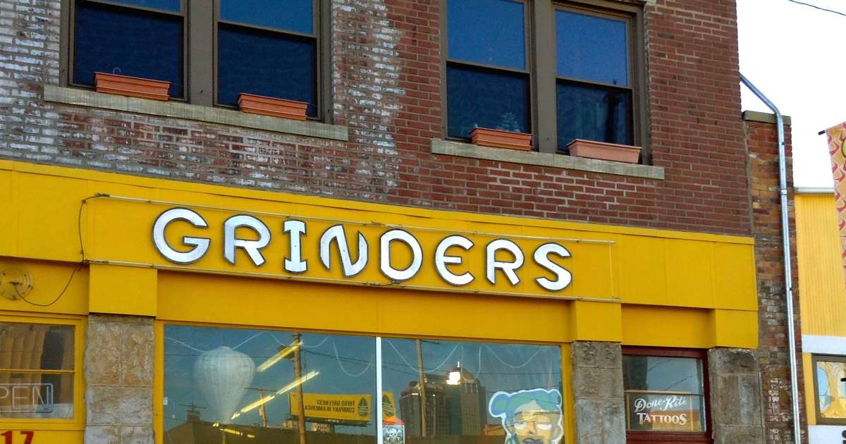 white sign outside of restaurant saying "GRINDERS"