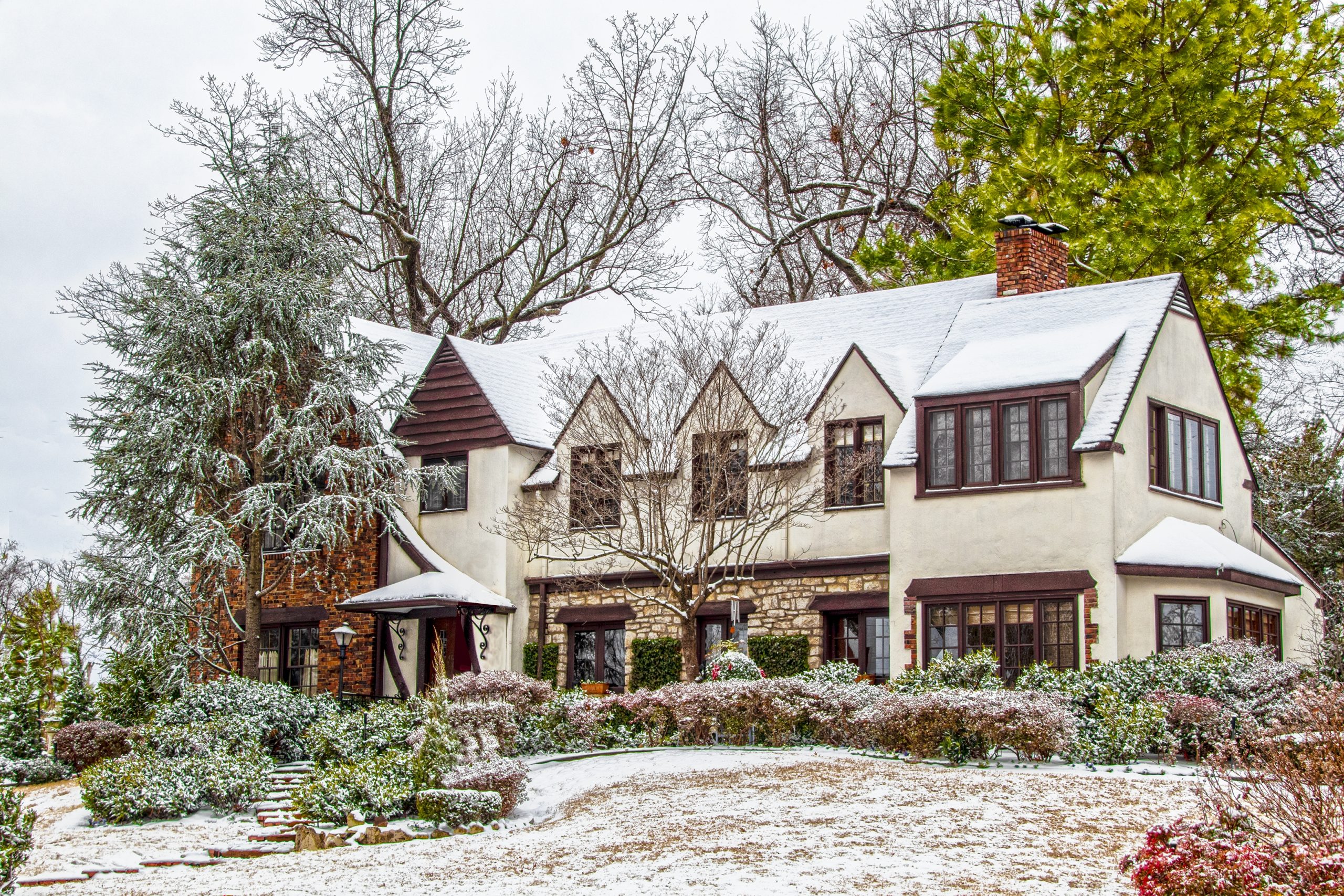 snow covered large house with trees