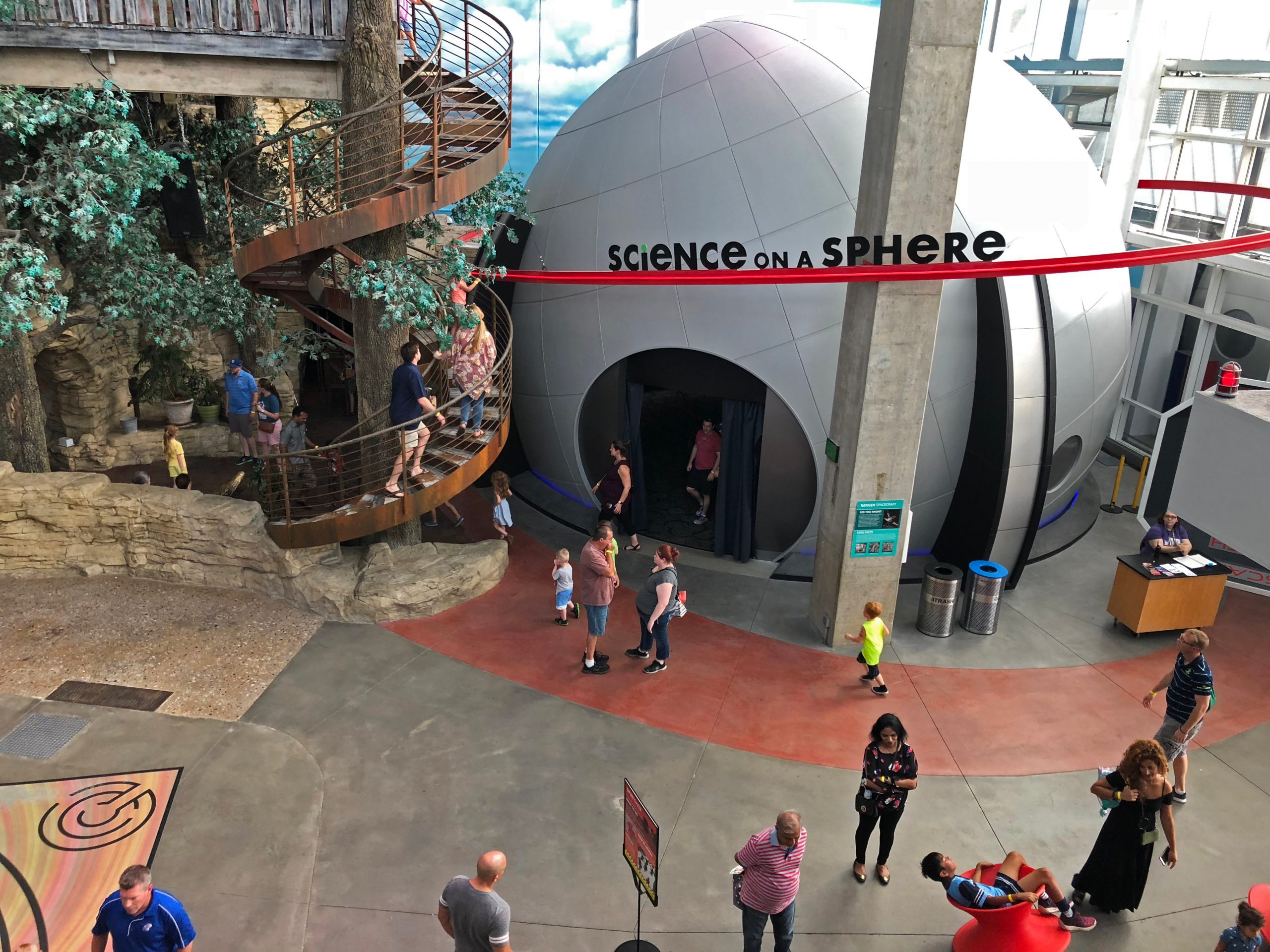 Adults and children exploring Science City inside Kansas City's Union Station, going up a winding staircase and inside a large globe