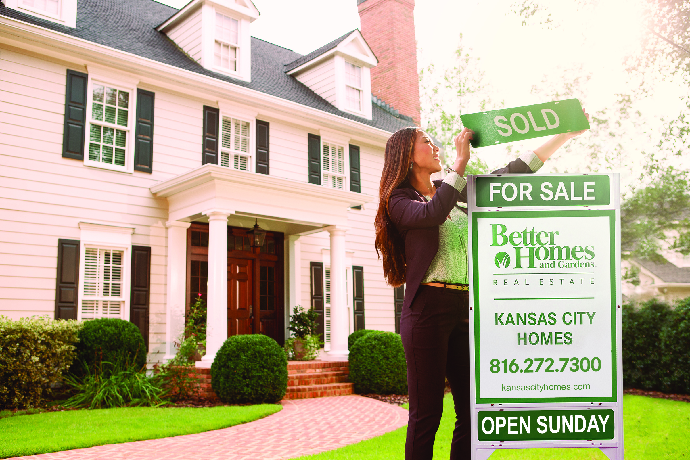 KCH Real Estate agent placing rider on yard sign in front of home