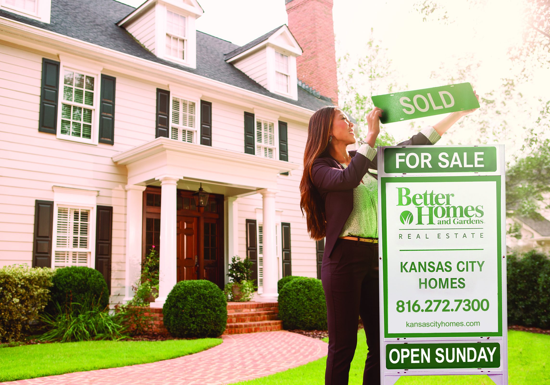 KCH Real Estate agent placing rider on yard sign in front of home